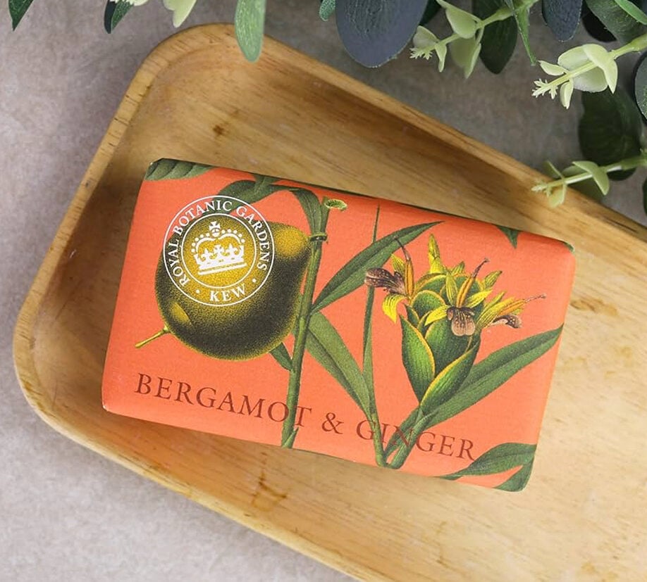 Royal Botanic Gardens Kew Bergamot & Ginger soap bar in orange floral packaging placed on a wooden dish.