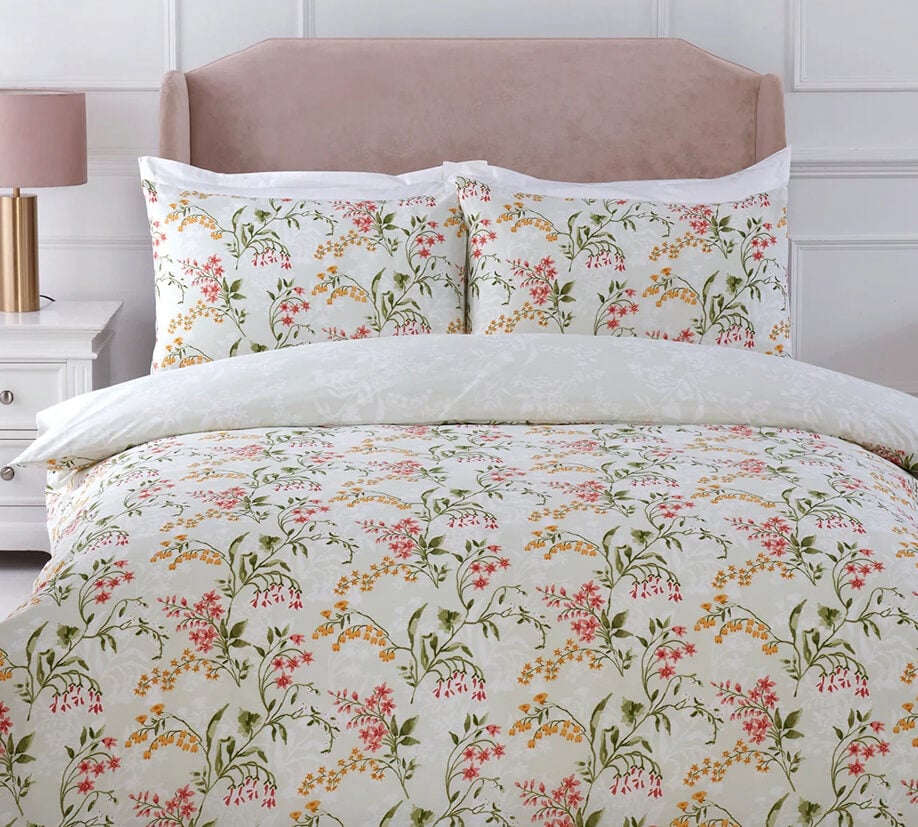 Elegant floral bedding set with white background and red, yellow, and green botanical print on a neatly made bed.