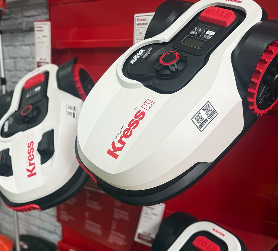 Display of Kress robotic lawn mowers with red and white design on shelves in a garden machinery section.