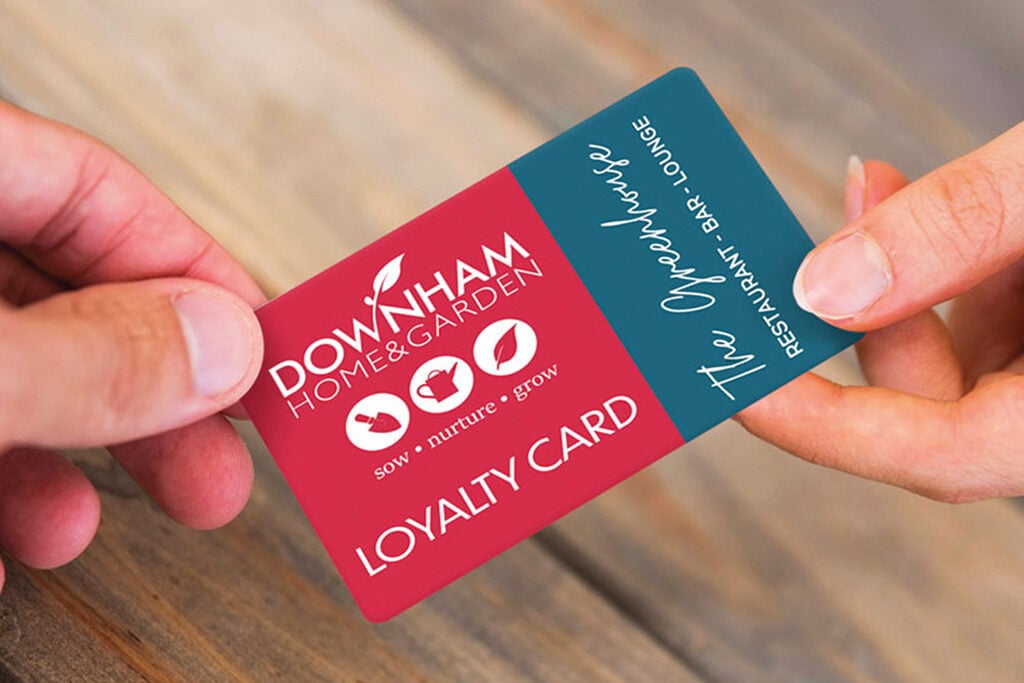 Close-up of a Downham Home & Garden loyalty card being handed from one person to another.